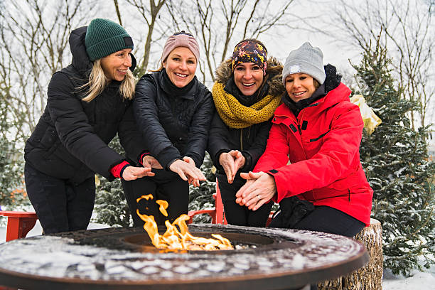 istock friends in winter coats sitting fire in forest 2247779749