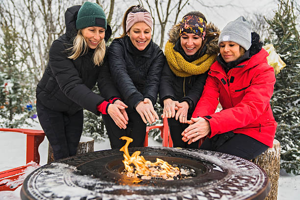 istock friends in winter coats sitting fire in forest 2247779769