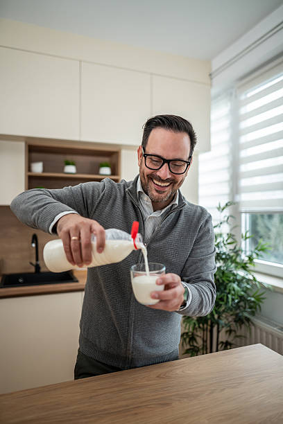 istock Happy man pouring milk into glass for breakfast 2247781417