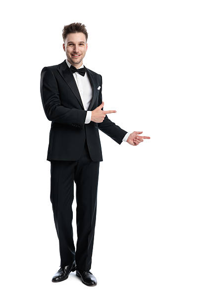 istock excited young groom in black tuxedo smiling and pointing fingers to side 2247783607