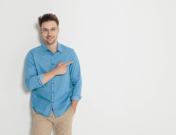 istock Smiling young casual man pointing finger to the side 2247784234