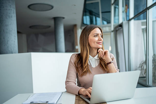 istock Businesswoman thinking and smiling while working at laptop 2247788584