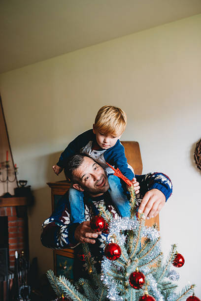 istock Father and son decorating christmas tree together at home 2247789200