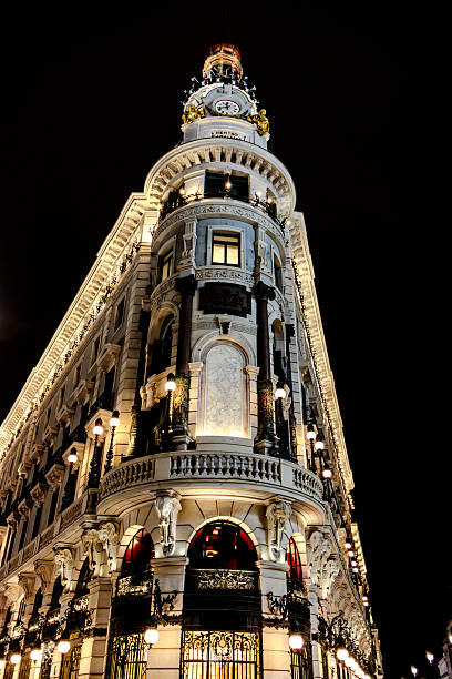 Historic residential building with classic European architecture illuminated at night in Madrid, Spain. Warm exterior lighting highlights the ornate facade, balconies, and traditional design, capturing the atmosphere of an urban street after dark.