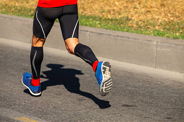 istock Legs runner  in compression socks runnning race, human shadow on asphalt 2247791577