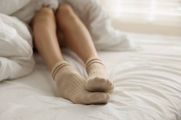 istock Woman in socks on bed at home, closeup 2247794232