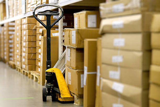 istock Manual Pallet Jack Waiting Amidst Cardboard Boxes in a Warehouse Aisle 2247797798