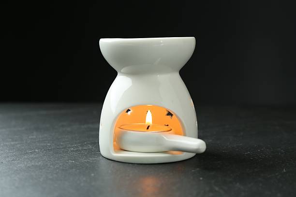 istock Aroma lamp with burning candle on dark textured table against black background, closeup 2247798465