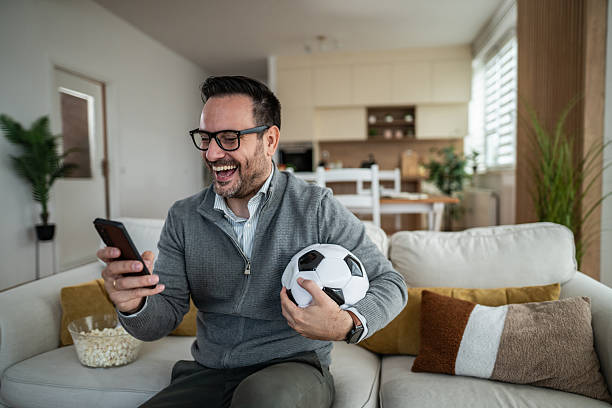 istock Man laughing at smartphone watching soccer 2247800895