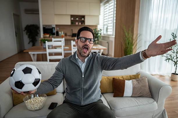 istock Man at home watching intense soccer game 2247800945