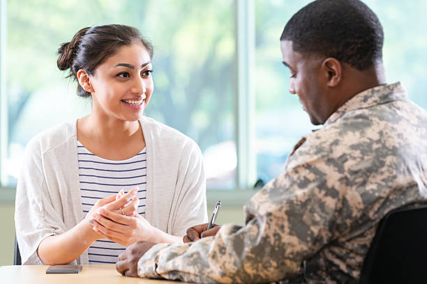 istock Woman and soldier having a supportive discussion indoors at a table, looking at each other. 2247804679
