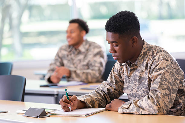 istock Young men in military uniforms focused on learning and working in a classroom setting. 2247804688