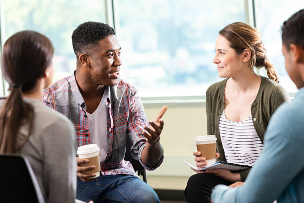 istock Diverse group in casual clothing engaging in conversation, holding coffee cups indoors. 2247807137