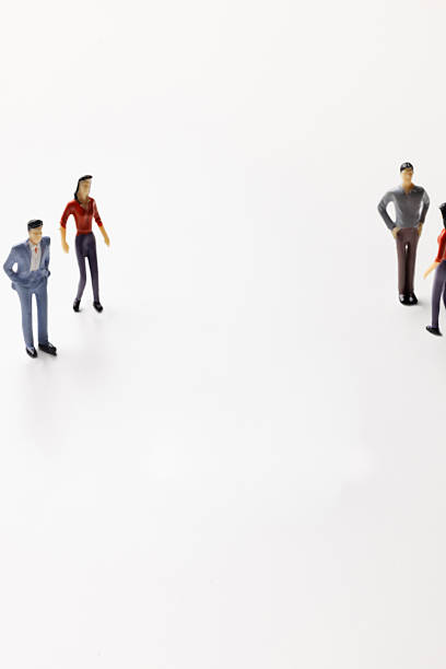istock Miniature figurines standing in two separate groups on a white background 2247811056