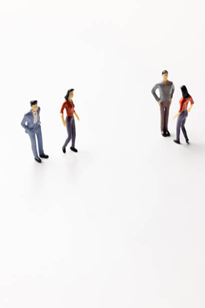 istock Miniature figurines standing in two separate groups on a white background 2247811062