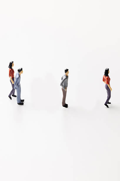 istock Miniature figurines standing in two separate groups on a white background 2247811318