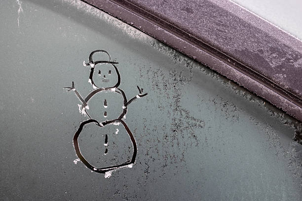 A stick figure snowman was scratched onto a frozen car window