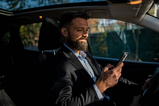 istock Young bearded businessman using smartphone in car 2247815706