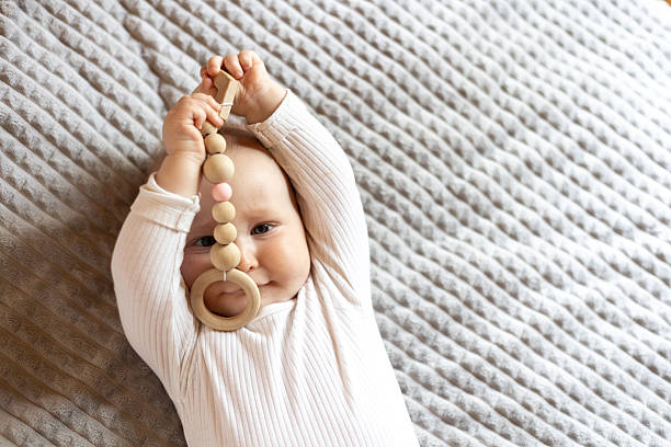 istock Baby Holding Wooden Toy While Lying on Blanket 2247819804
