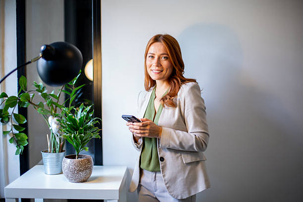 istock Businesswoman smiling and using smartphone in modern office 2247821005
