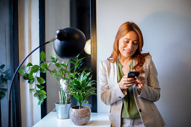 istock Businesswoman smiling while texting on smartphone in office 2247821118