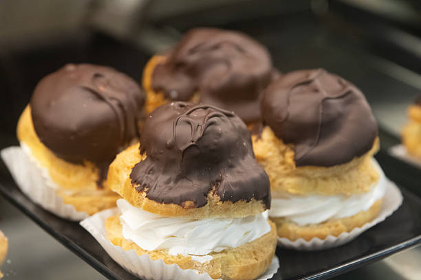 Cream-filled pastry delicacies displaying vanilla cream filling, powdered sugar coating, arranged against pristine white tiled surface