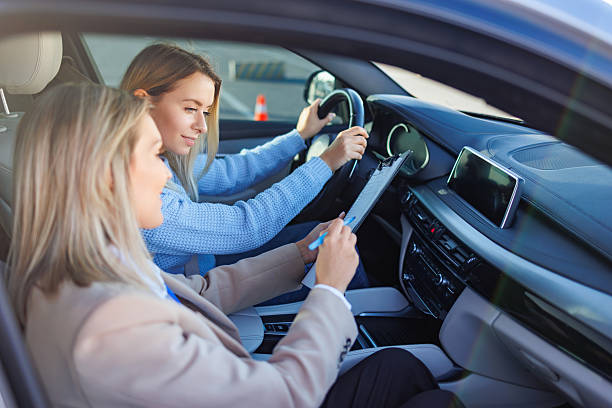 istock Driving Examiner Reviewing Tasks with Student During Road Test 2247823281