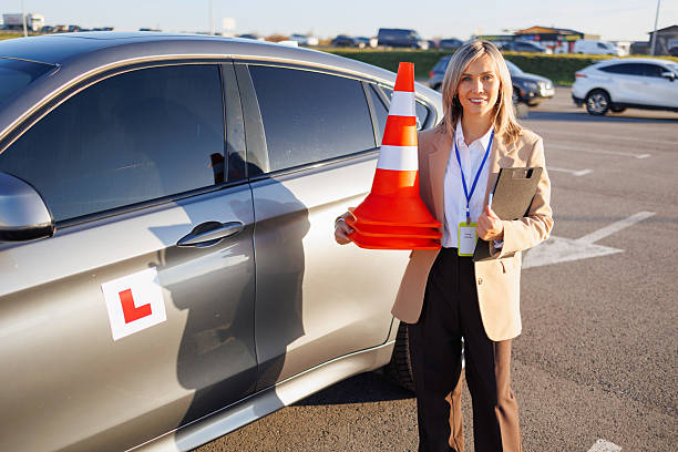 istock Driving Instructor Holding Cones Beside Training Car in Parking Lot 2247823367