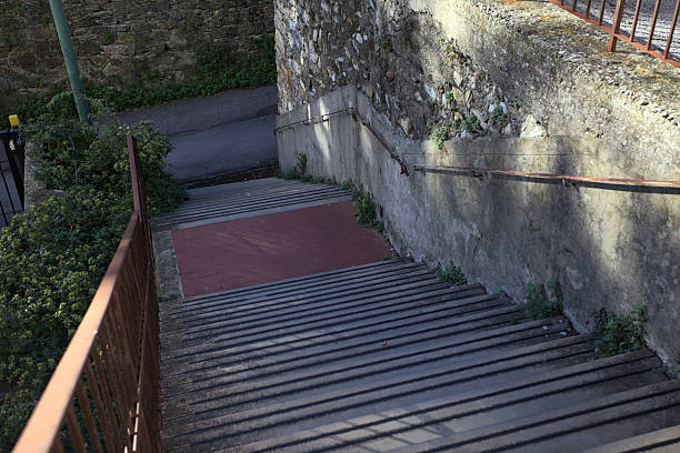 Concrete staircase with grass on its edge in the shade next to edge of a road
