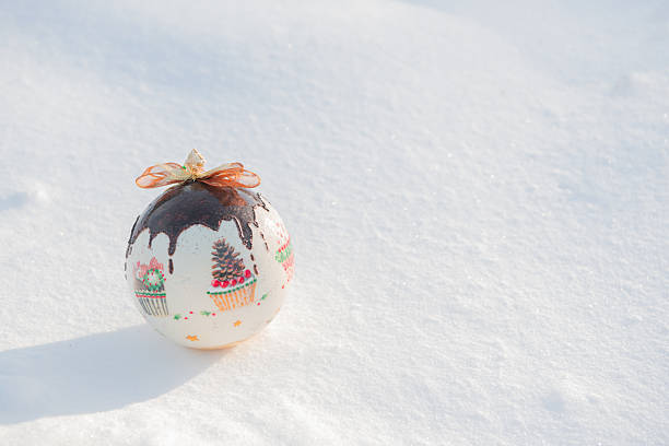 Christmas card. Christmas bauble lying on natural snow on a frosty sunny day, with decorative stars.
