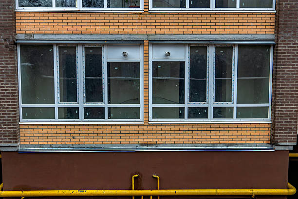 istock The image shows a building with a brick facade and a row of windows with white frames some of which are partially obscured by a yellow pipe running along the bottom of the building 2247826555