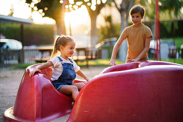 Kids enjoying outdoor playtime on a spinning carousel at sunset.