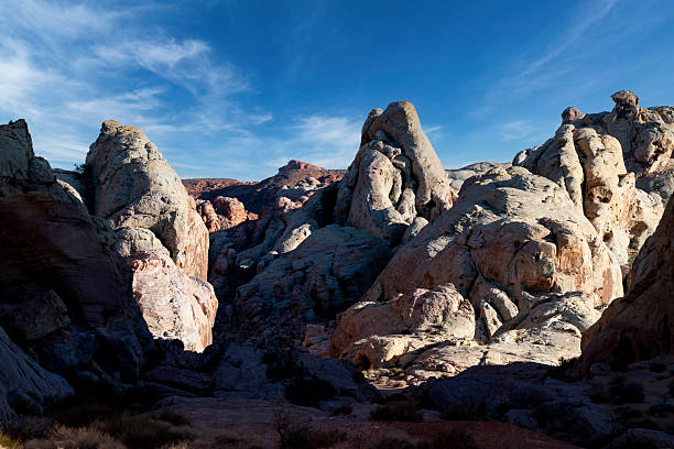 As daylight fades over Valley of Fire State Park, the park's red sandstone formations glow beneath a blue evening sky. The waning sunlight highlights the desert landscape, balancing warm stone against a cooling sky. The scene captured the quiet transition between day and night in one of Nevada's most striking desert environments.