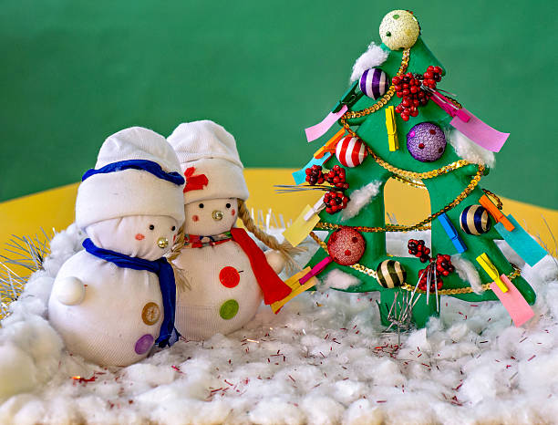A couple of snowmen sitting next to a christmas tree in the snow