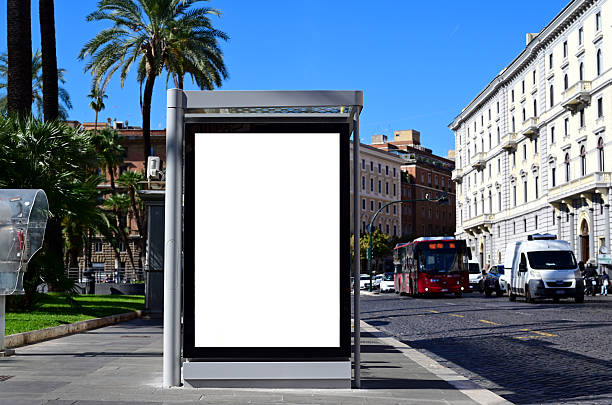 istock blank billboard, lightbox. ad panel along sidewalk. palm trees. outdoor advertising sign mockup. Italian street scene 2247832375