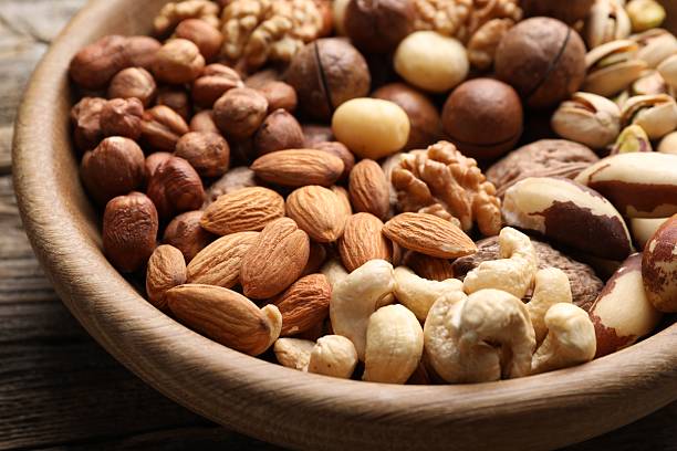 istock Mix of different nuts in bowl on wooden table, closeup 2247833055