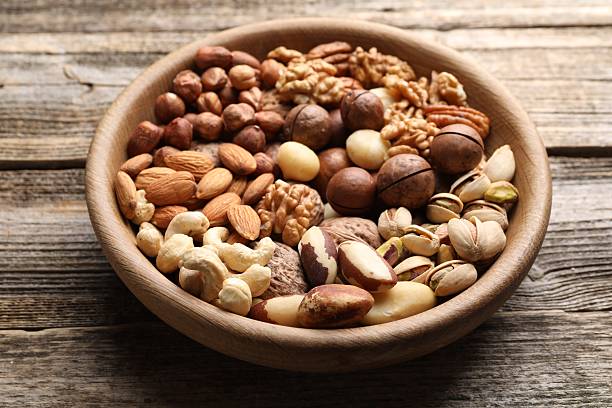 istock Mix of different nuts in bowl on wooden table, closeup 2247833081