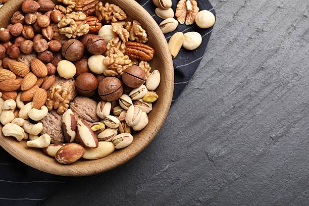 istock Mix of different nuts in bowl on black table, top view. Space for text 2247833091