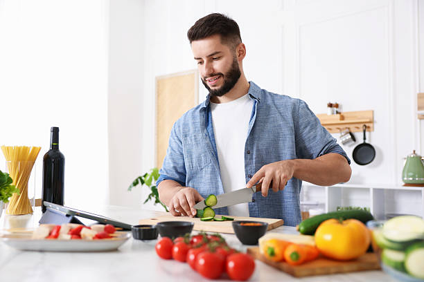 istock Smiling man looking at recipe on tablet while cooking at table in kitchen 2247833575