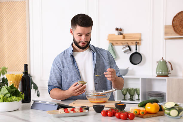 istock Cooking process. Young man seasoning dish at table in kitchen 2247833870