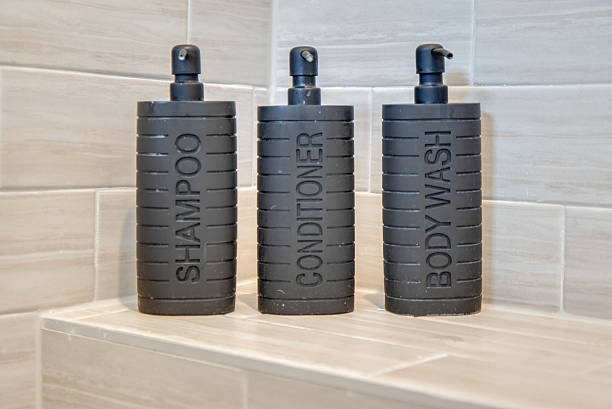 A trio of black soap dispensers for shampoo, conditioner, and body wash in a shower