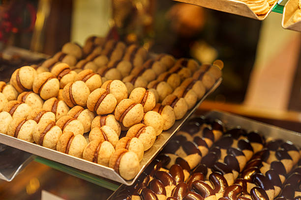 A display of cookies with different toppings, including chocolate chips and nuts. The tray with nuts is at the bottom of the display.