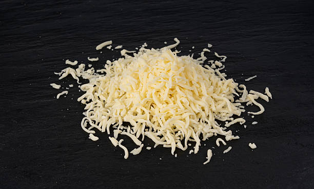 istock Grated mozzarella cheese on black background. Shredded mozarella texture 2247841632