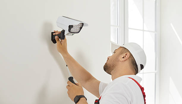istock Electrician worker installs and screws video surveillance camera with backlight on wall. 2247845016