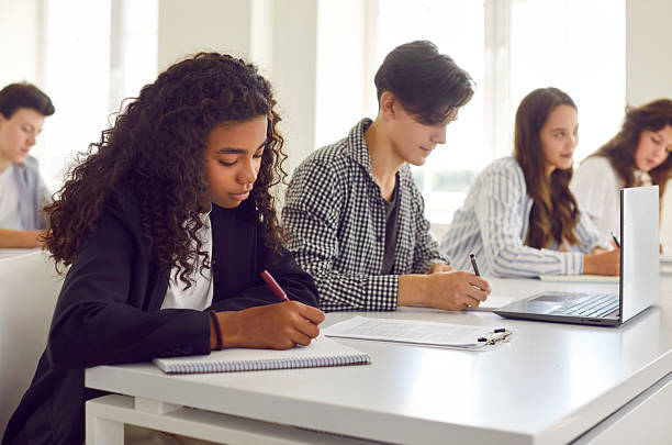 istock Side view of a group of young students writing notes during a lesson in the classroom. 2247846809