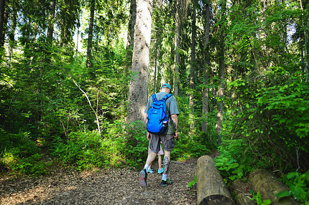 istock Man and child hiking through green forest trail 2247850071