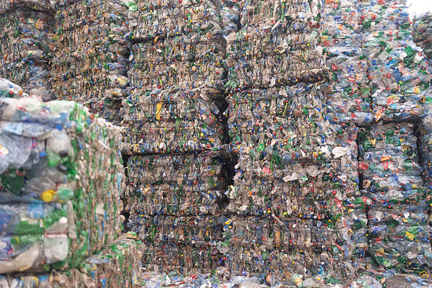 istock Piles of compacted plastic bottles bound together in heavy bales, stored outdoors under daylight 2247856563
