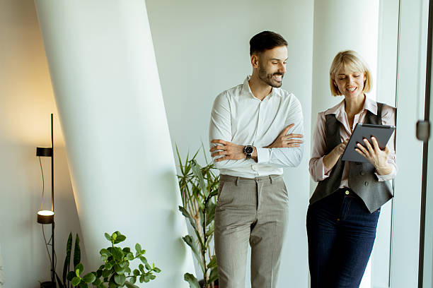 istock Smiling colleagues discussing project details by the large windows in a modern office 2247856670