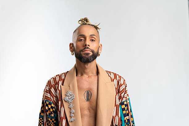 Confident black gay man standing isolated on white background, dressed in a bold, colorful jacket. Exudes sense of pride and individuality. Diversity power of personal style
