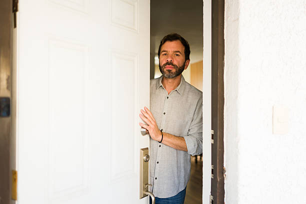 Man with beard opening his house door, checking outside. Greeting someone or seeing who is ringing his doorbell